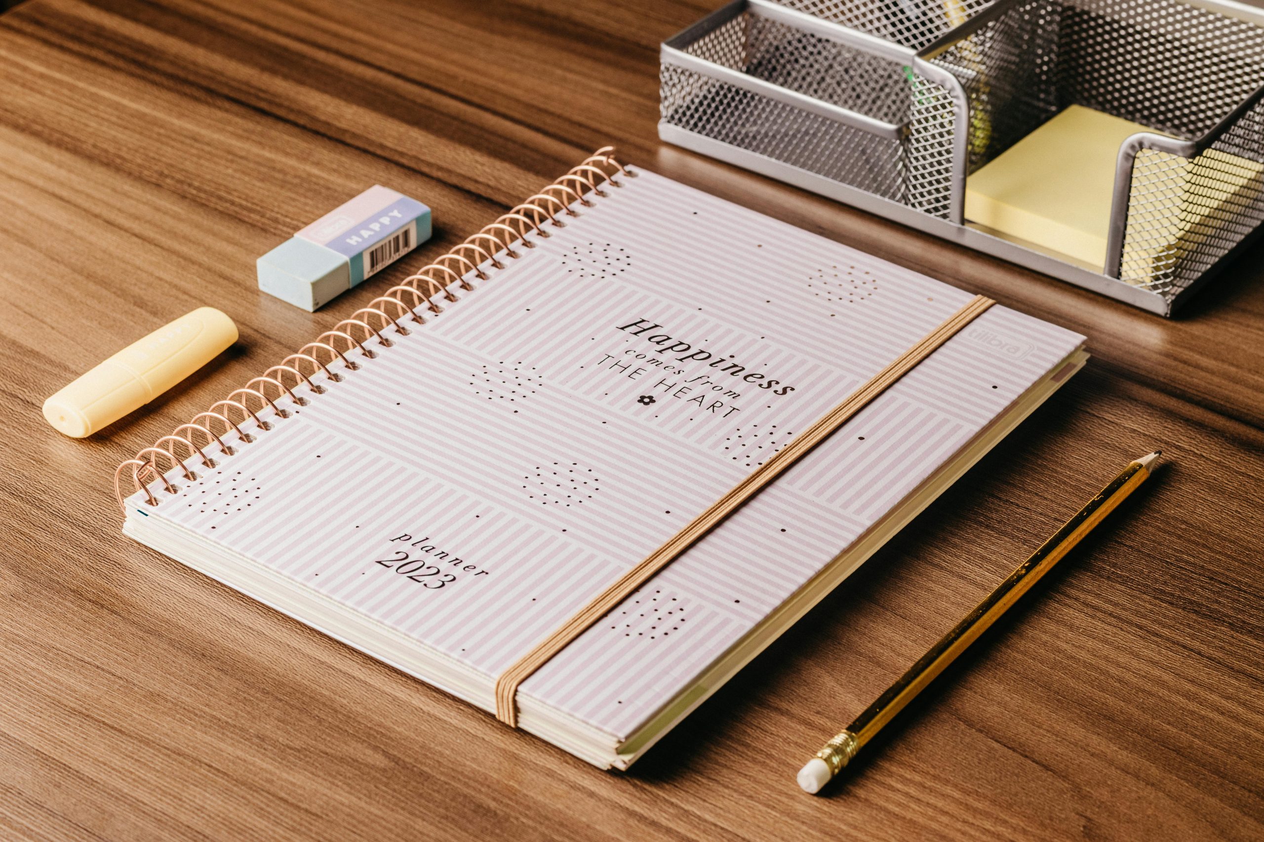 Minimalist 2023 planner with stationery on a wooden desk, perfect for organizational themes.
